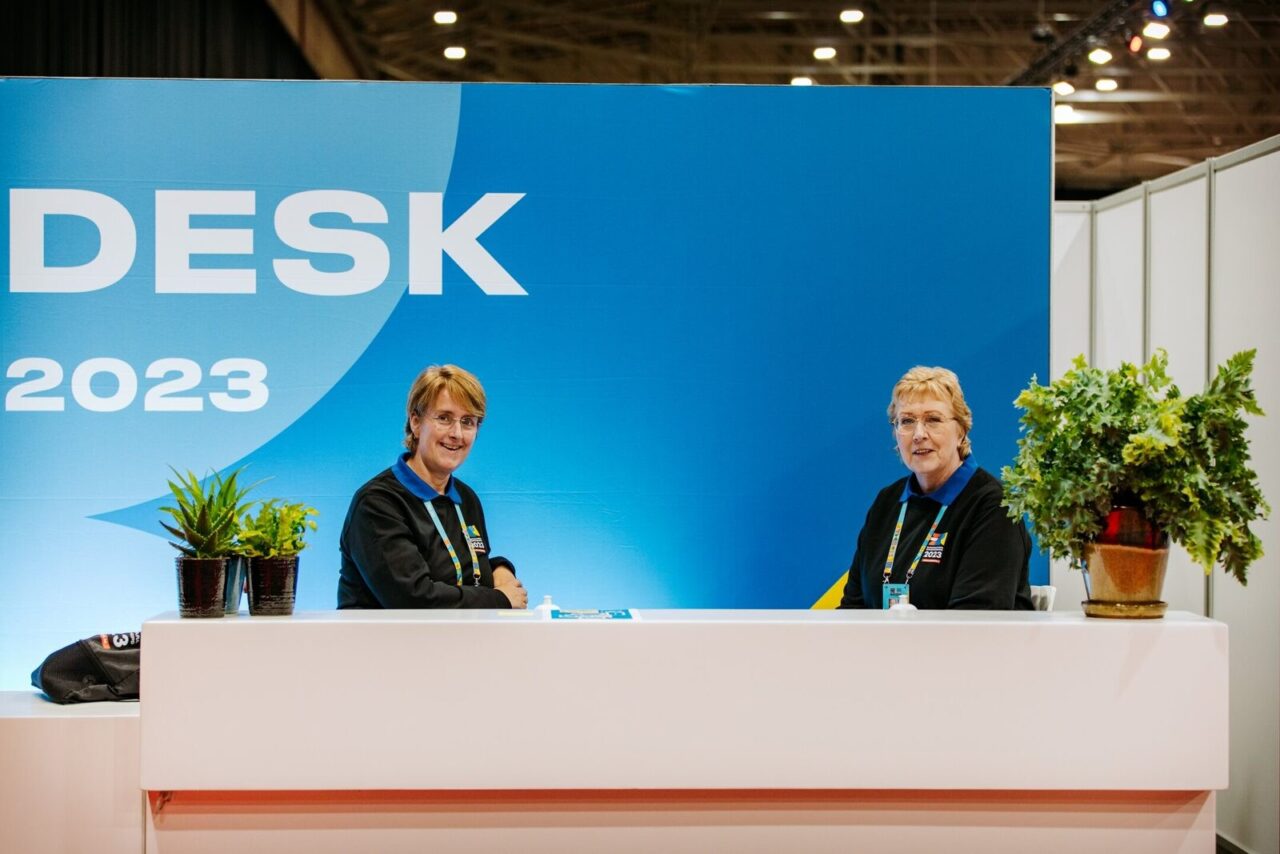 Two EPC 2023 volunteers smile behind the information desk.